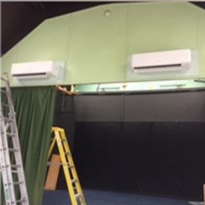 Two air conditioning units on green wall
